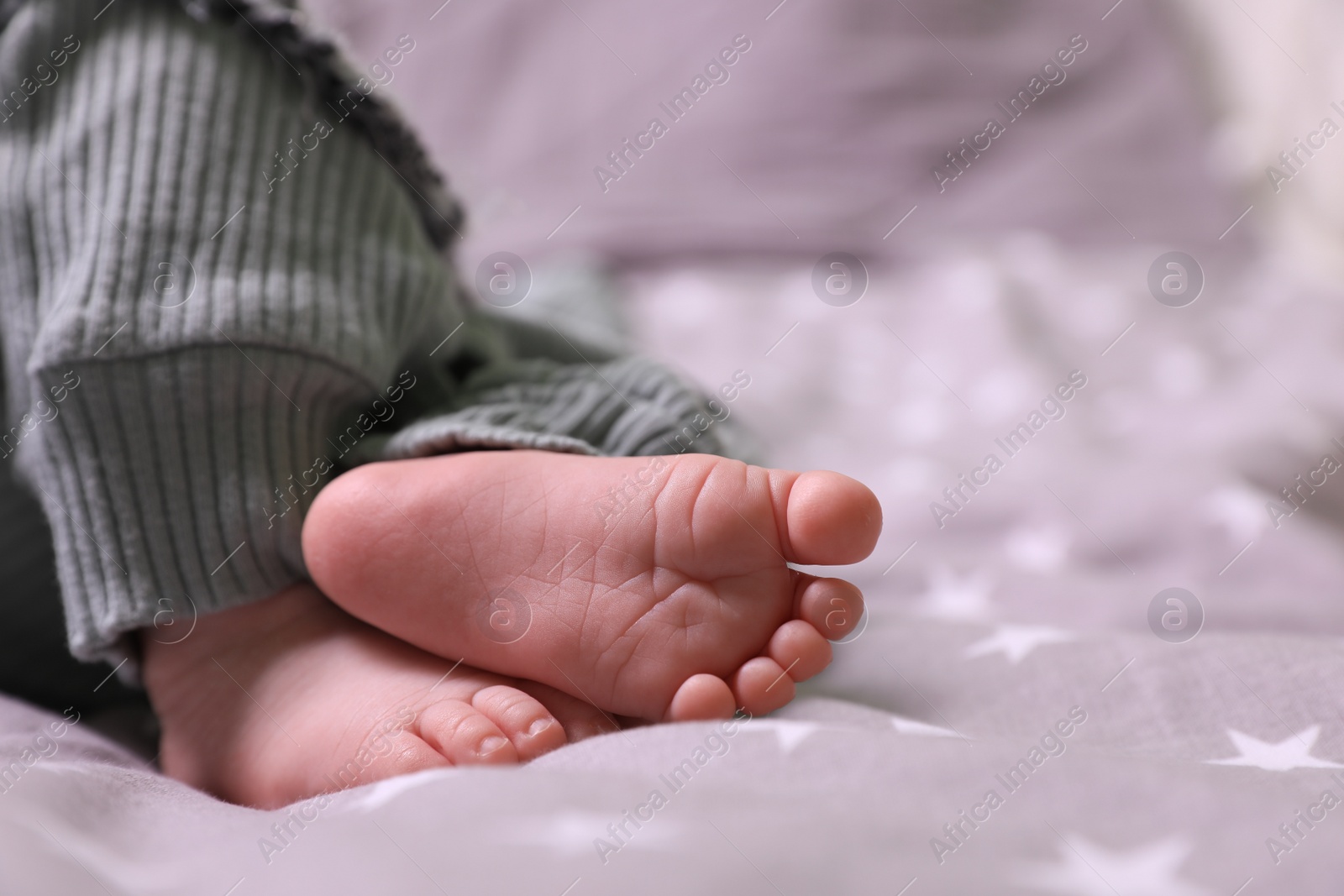 Photo of Cute newborn baby lying on bed, closeup of legs. Space for text