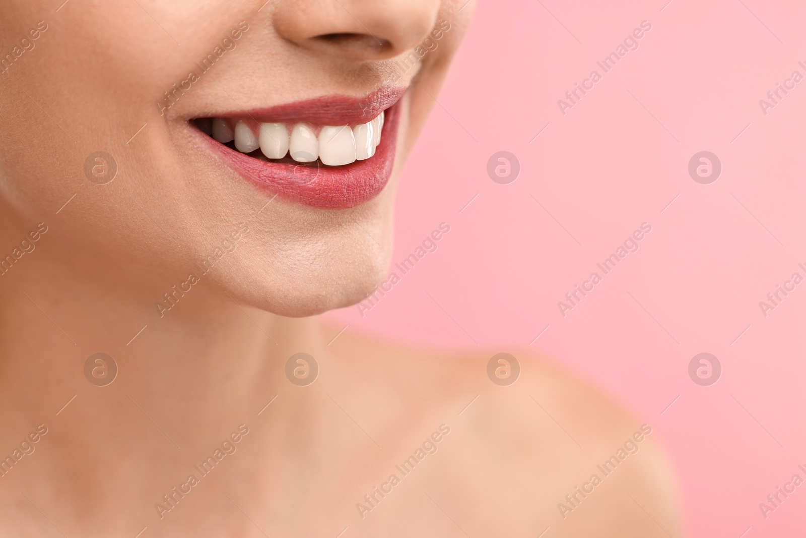 Photo of Woman with beautiful lips smiling on pink background, closeup. Space for text