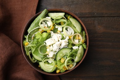 Photo of Bowl of tasty salad with leek and cheese on wooden table, top view