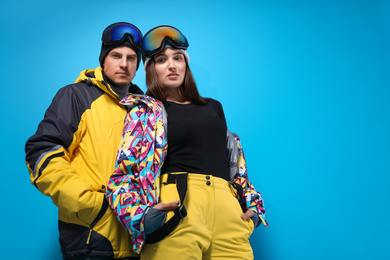 Photo of Couple wearing stylish winter sport clothes on light blue background, low angle view