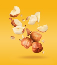 Image of Pieces of tasty hazelnuts falling on yellow background