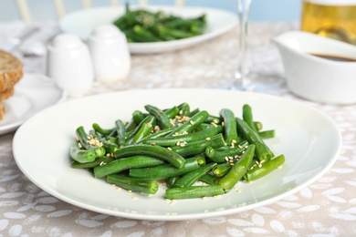 Tasty green beans with sesame seeds served for dinner on table