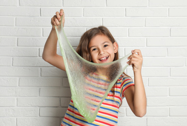 Little girl with slime near white brick wall