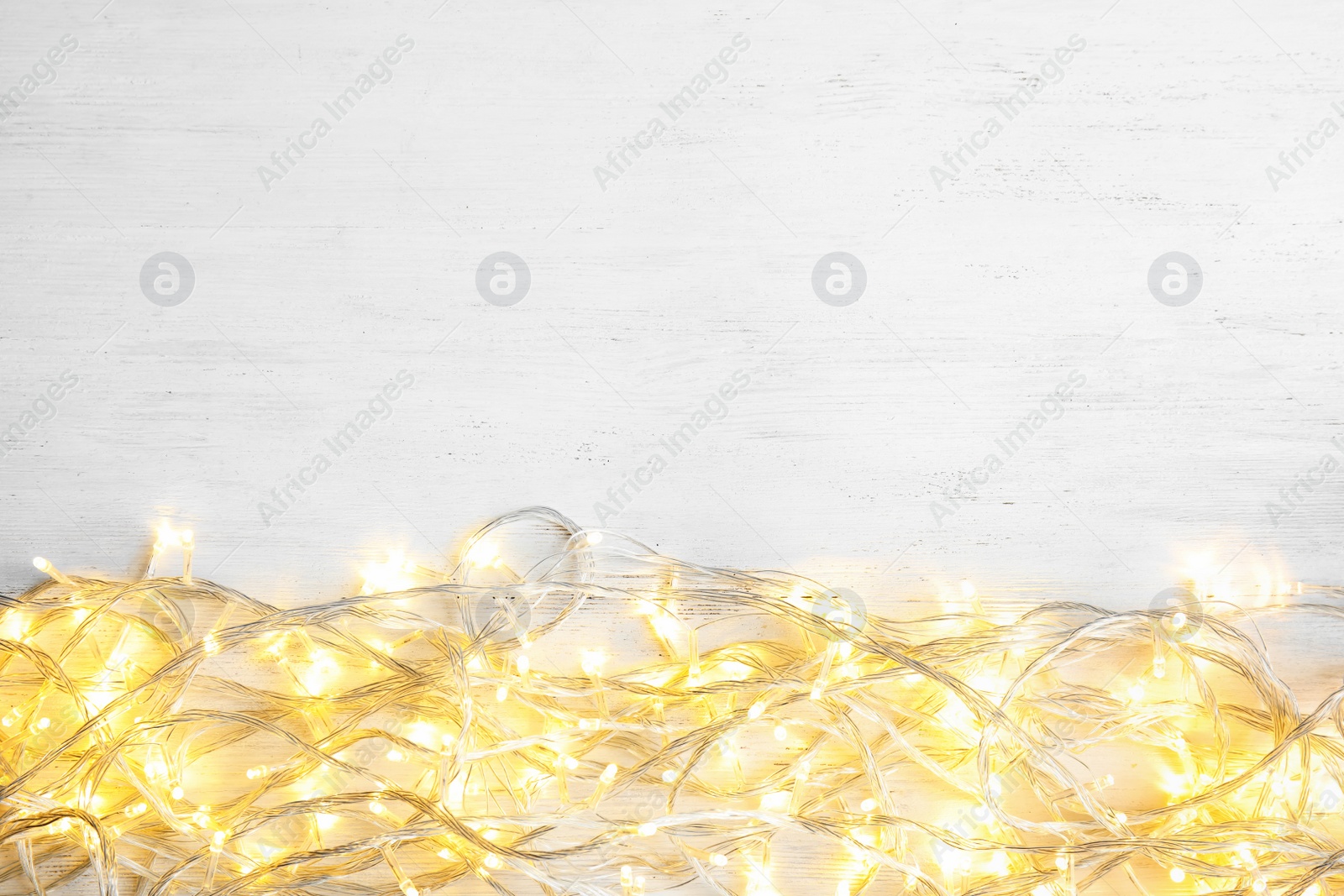 Photo of Glowing Christmas lights on wooden background, top view