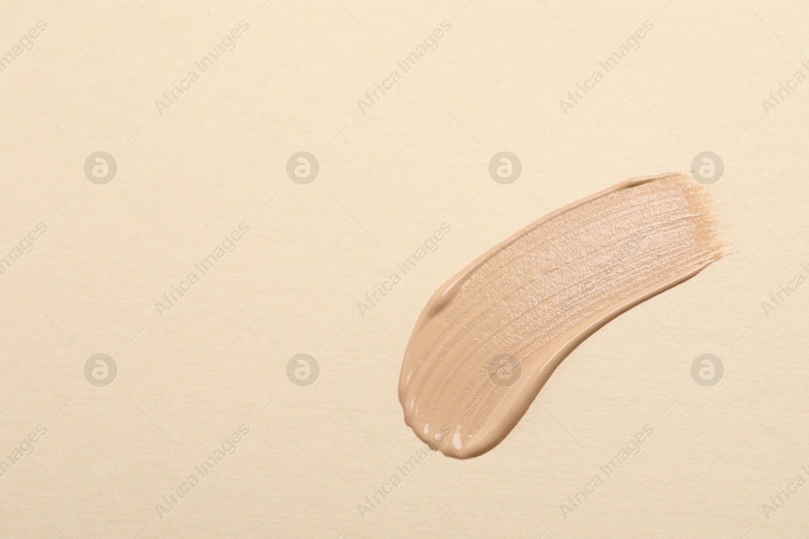 Photo of Smear of skin foundation on beige background, top view. Space for text