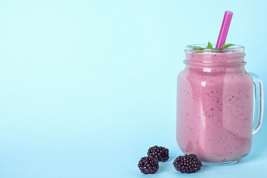 Delicious blackberry smoothie in mason jar on light blue background. Space for text