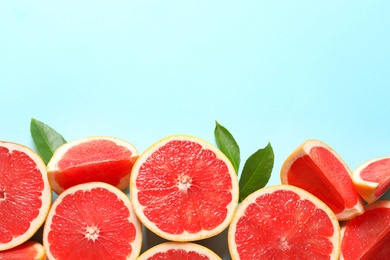 Fresh grapefruits and leaves on color background, flat lay with space for text. Citrus fruits