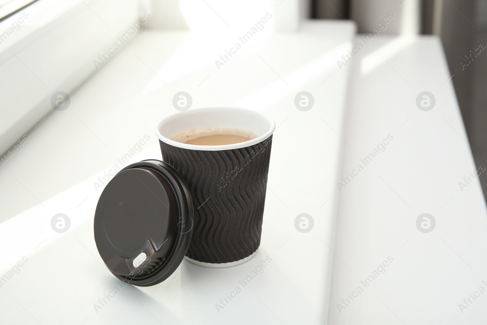 Photo of Cardboard cup of coffee on window sill indoors