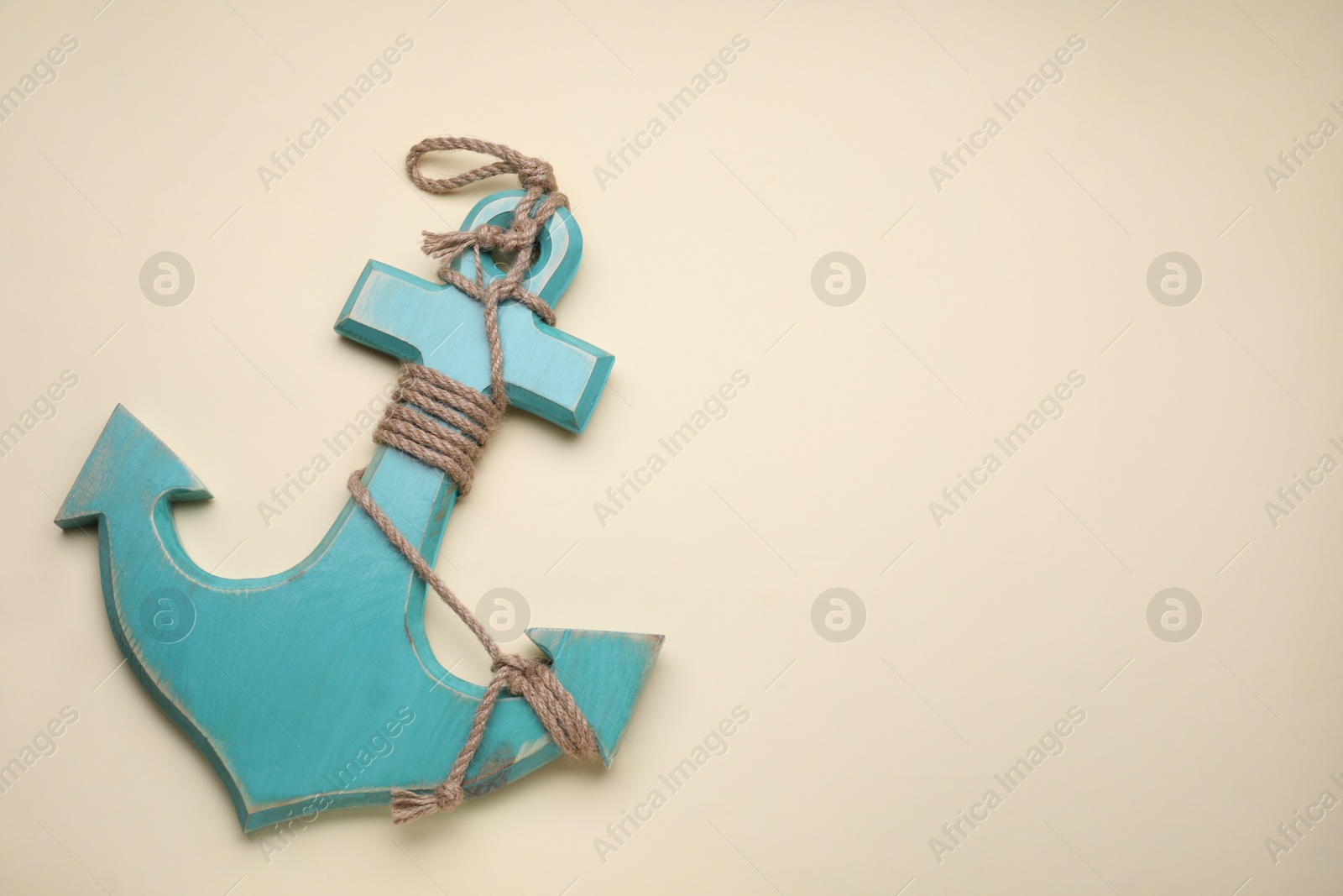 Photo of Wooden anchor with hemp rope on beige background, top view. Space for text