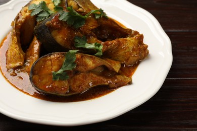 Photo of Tasty fish curry on wooden table, closeup. Indian cuisine