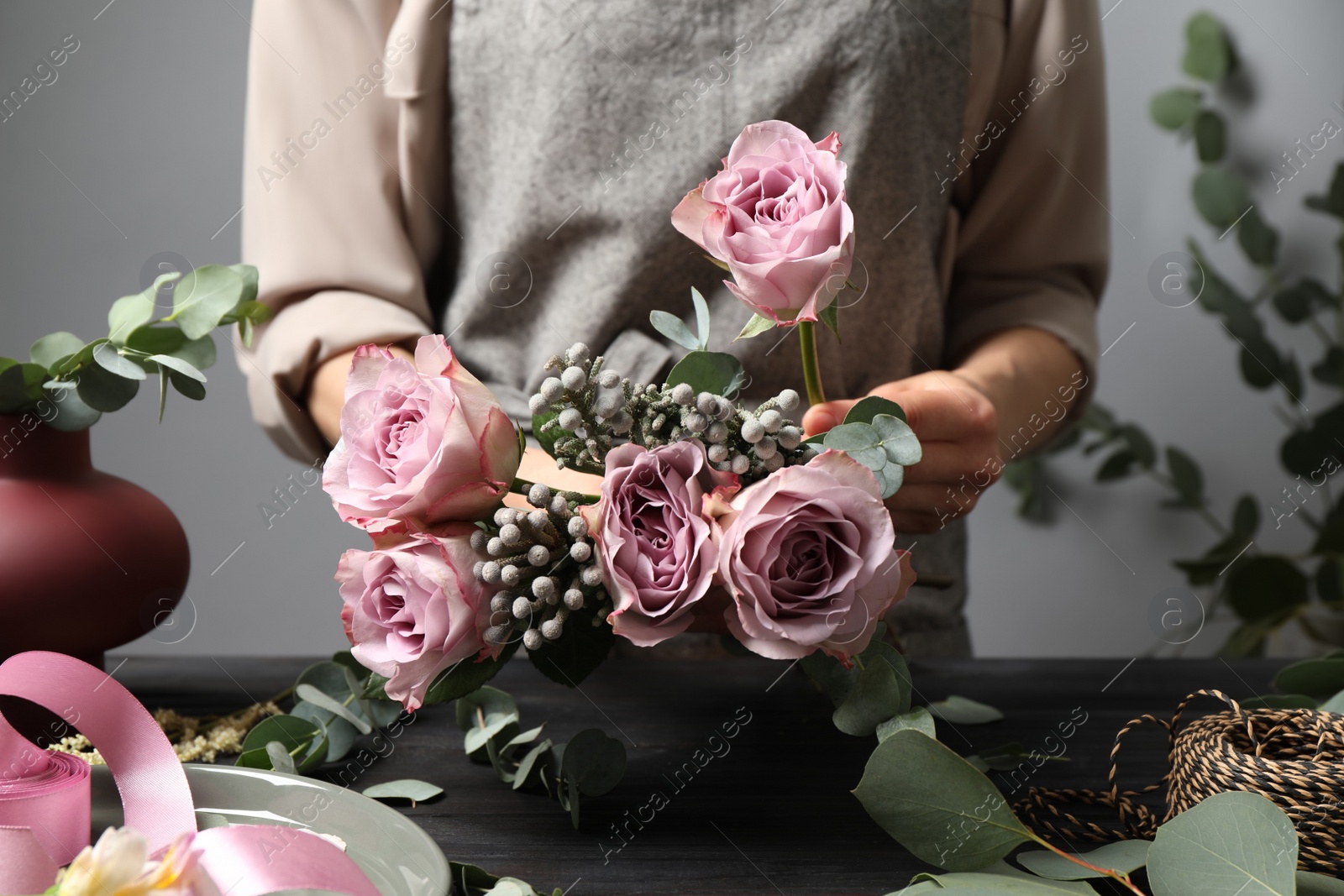 Photo of Florist creating beautiful bouquet at black wooden table indoors, closeup