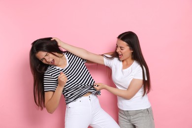 Photo of Aggressive young women fighting on pink background