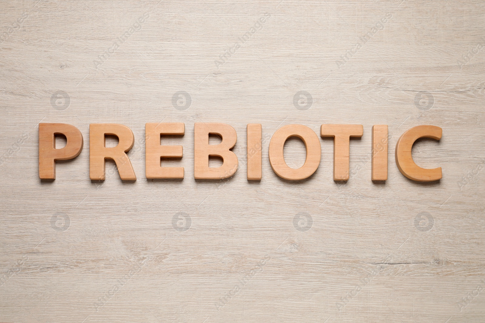 Photo of Word Prebiotic made of letters on wooden table, top view