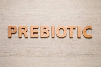 Photo of Word Prebiotic made of letters on wooden table, top view