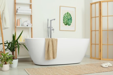 Stylish bathroom interior with beautiful tub and houseplants