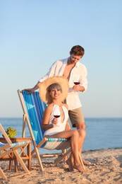 Photo of Young couple with glasses of wine on beach