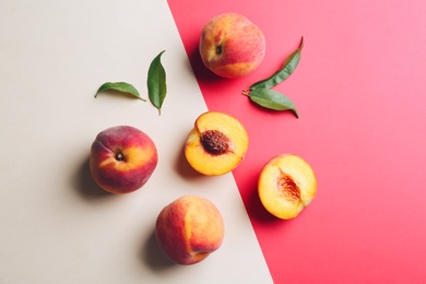 Photo of Fresh ripe peaches and green leaves on color background, flat lay