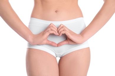 Photo of Young woman making heart symbol with hands near underwear on white background. Gynecology