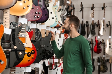 Buyer choosing guitar in modern music store