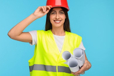 Photo of Architect in hard hat with drafts on light blue background