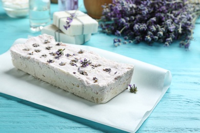 Photo of Hand made soap bar with lavender flowers on light blue wooden table