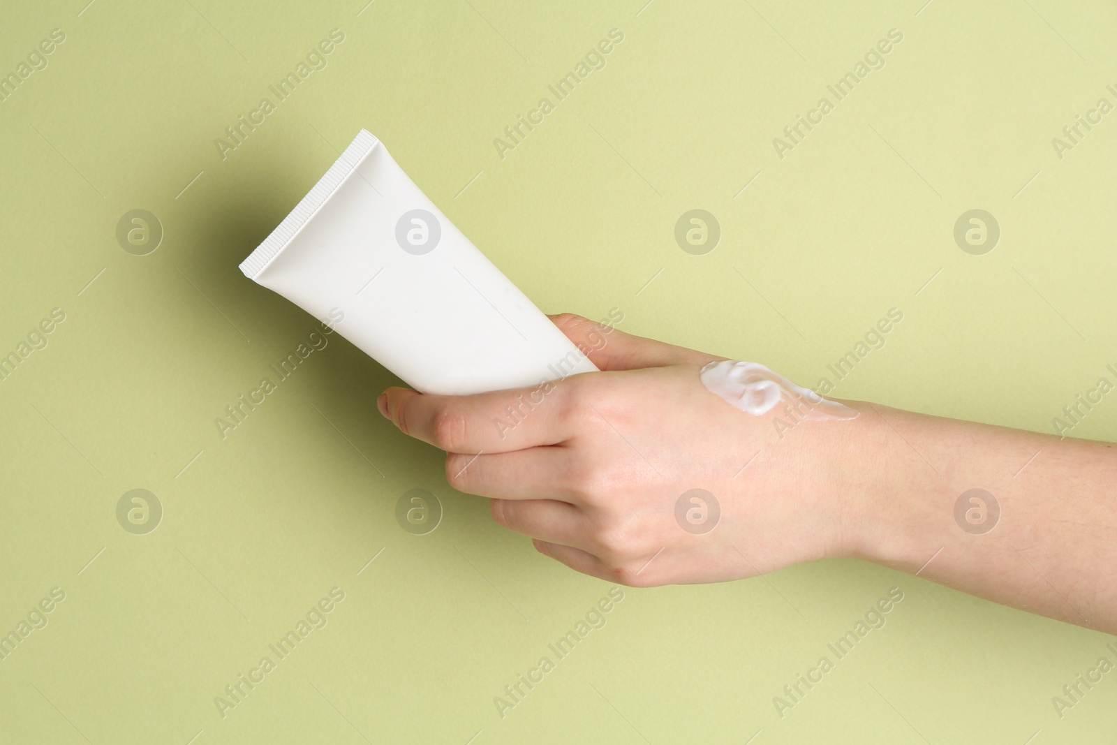 Photo of Woman with tube of cream on green background, closeup