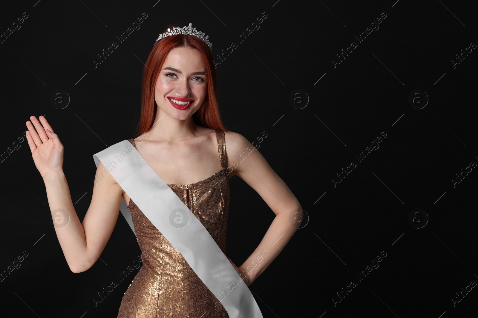 Photo of Beautiful young woman with tiara and ribbon in dress on black background, space for text. Beauty contest