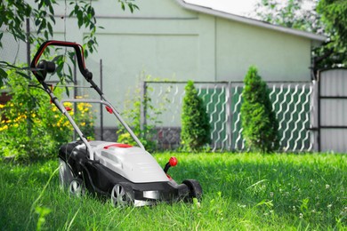 Photo of Lawn mower on green grass in garden, space for text
