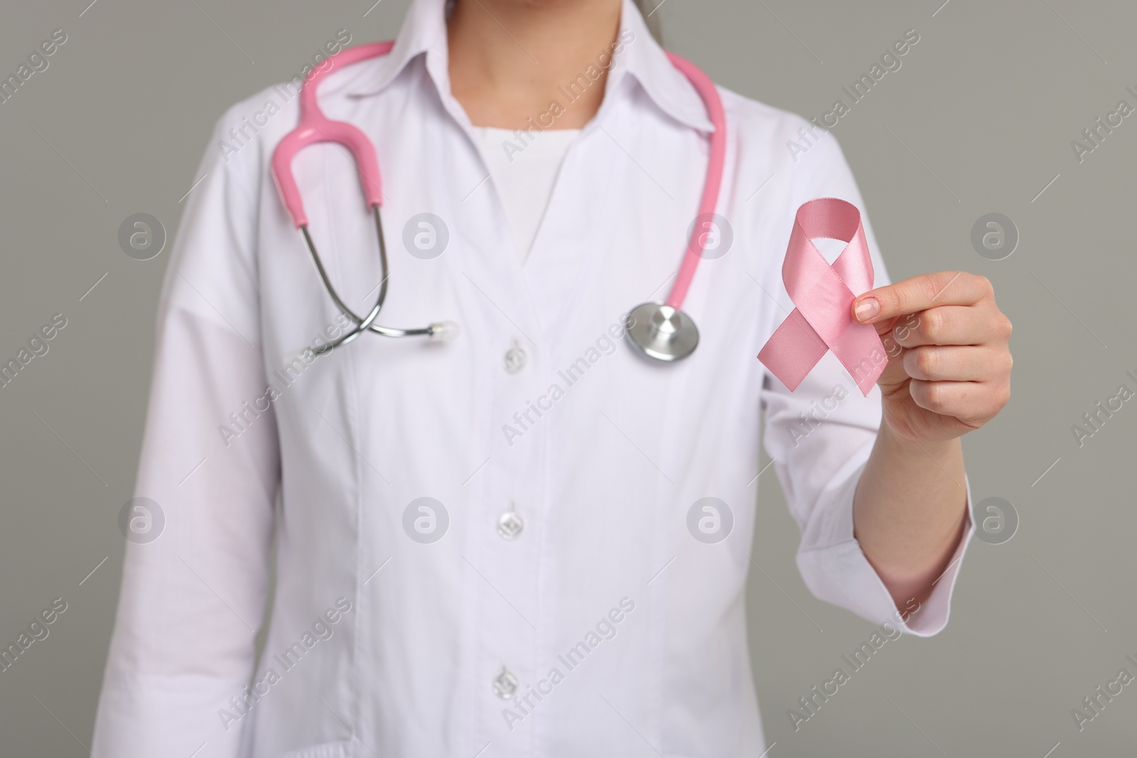 Photo of Mammologist with pink ribbon on gray background, closeup. Breast cancer awareness
