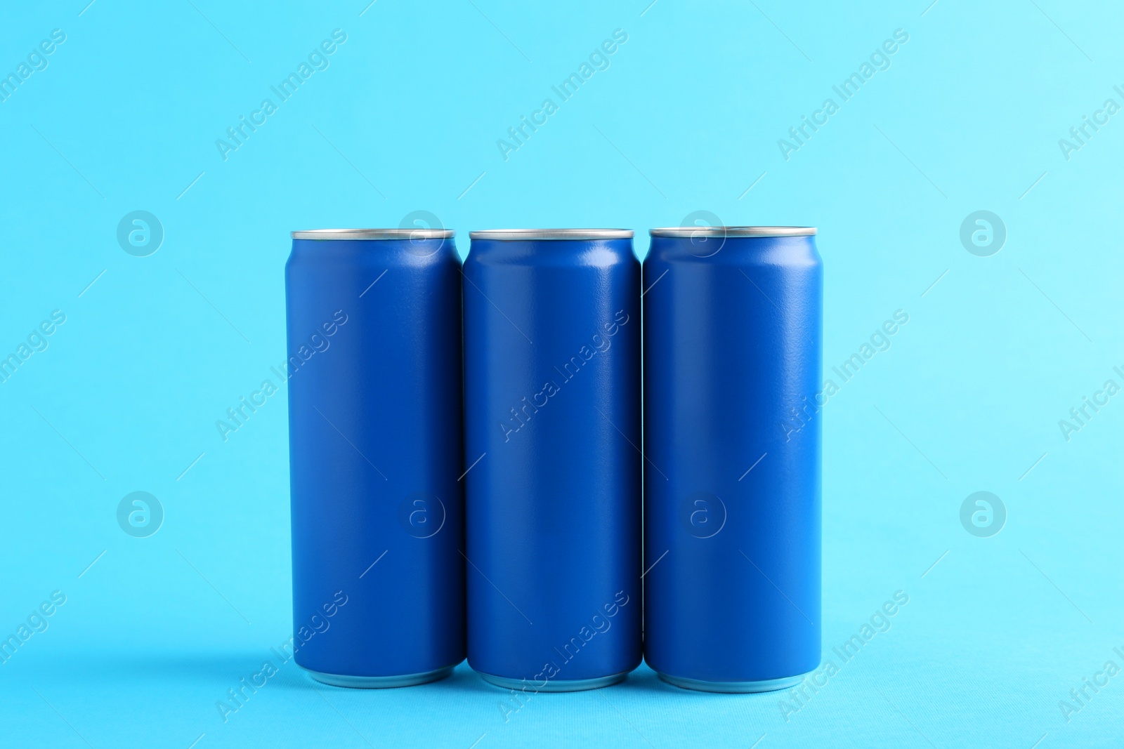Photo of Energy drinks in cans on light blue background