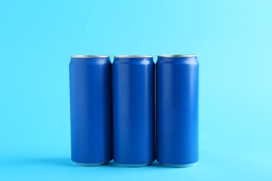 Energy drinks in cans on light blue background