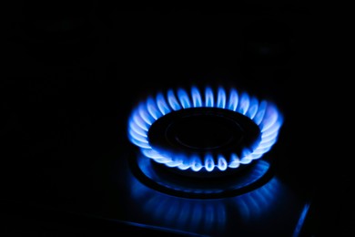 Photo of Gas cooktop with burning flame in darkness