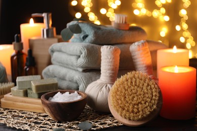 Photo of Beautiful composition with different spa products and burning candles on table against blurred lights