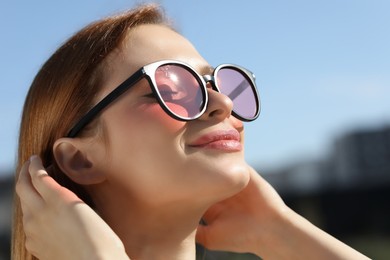 Photo of Beautiful woman in sunglasses outdoors, closeup. Space for text