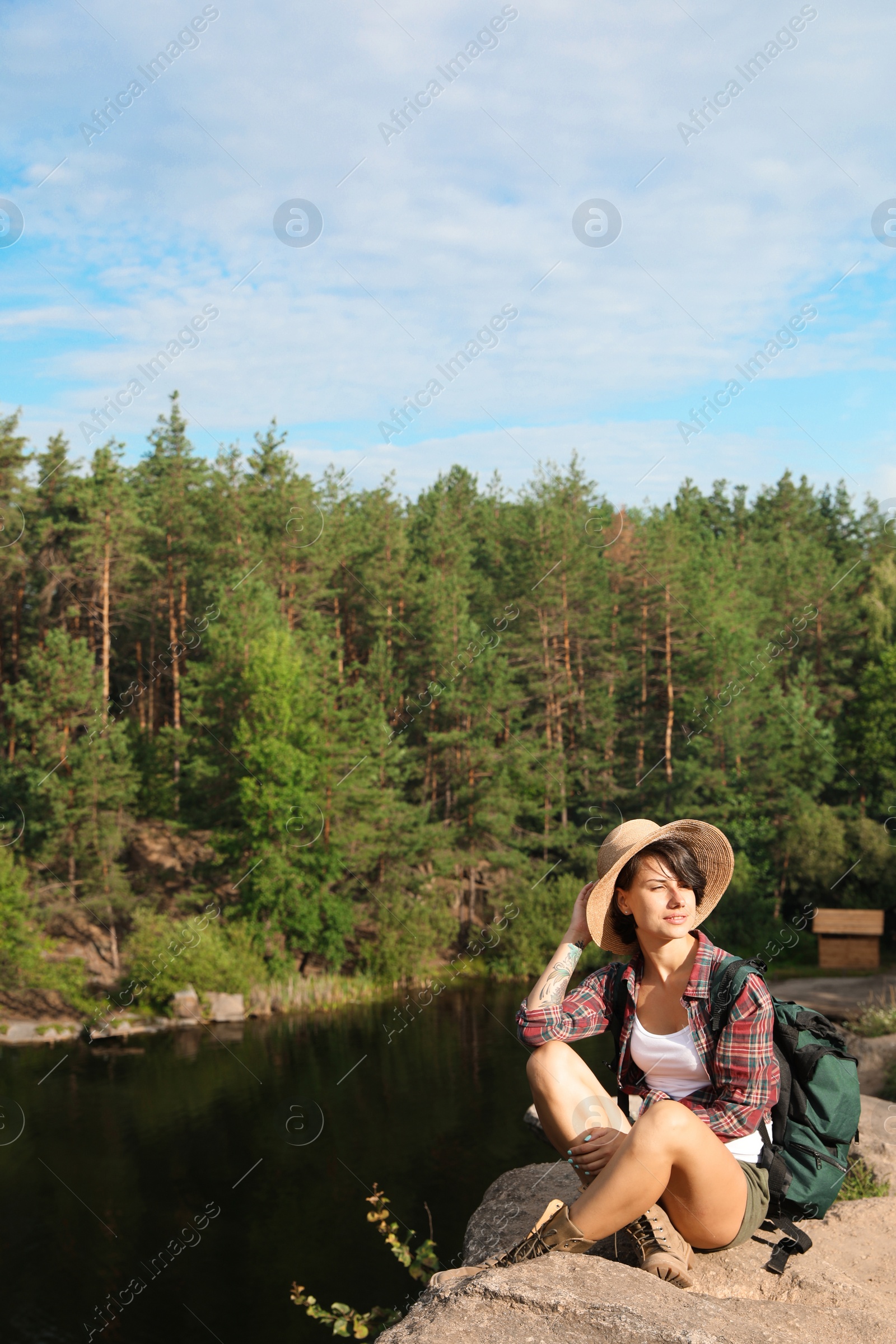 Photo of Young woman on rock near lake and forest. Camping season