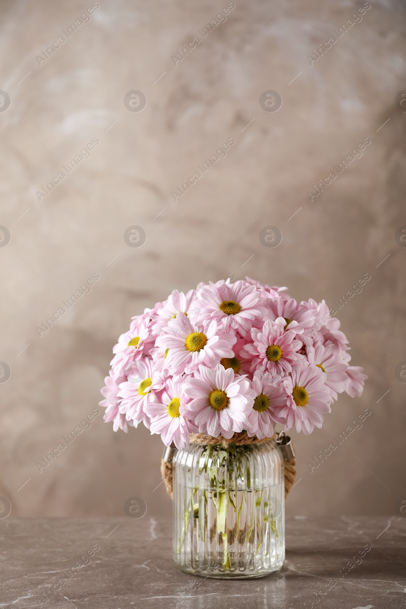 Photo of Vase with beautiful chamomile flowers on table against color background