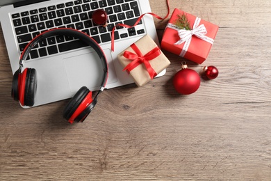 Flat lay composition with headphones on wooden background, space for text. Christmas music