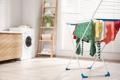 Photo of Different apparel drying on clothes airer in bathroom, space for text
