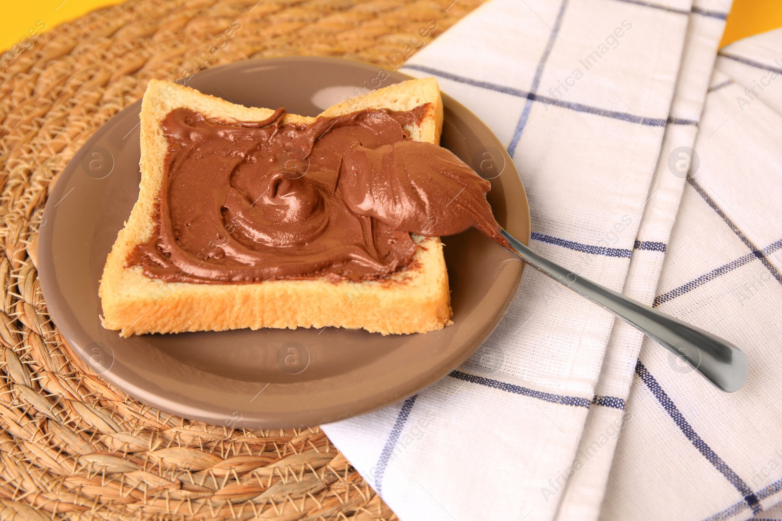 Photo of Tasty toast with chocolate paste and napkin on wicker mat, closeup