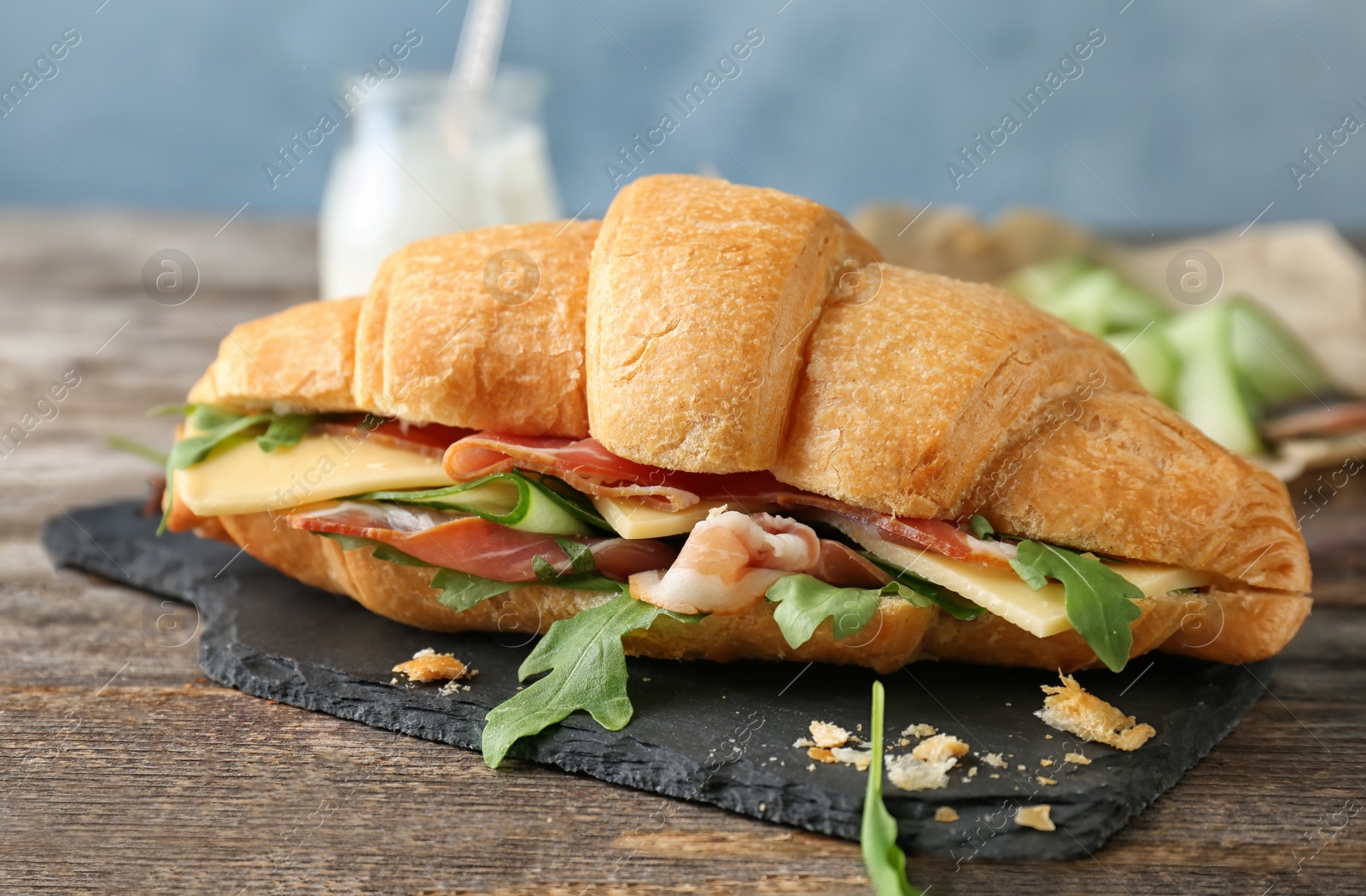 Photo of Tasty croissant sandwich with bacon on table