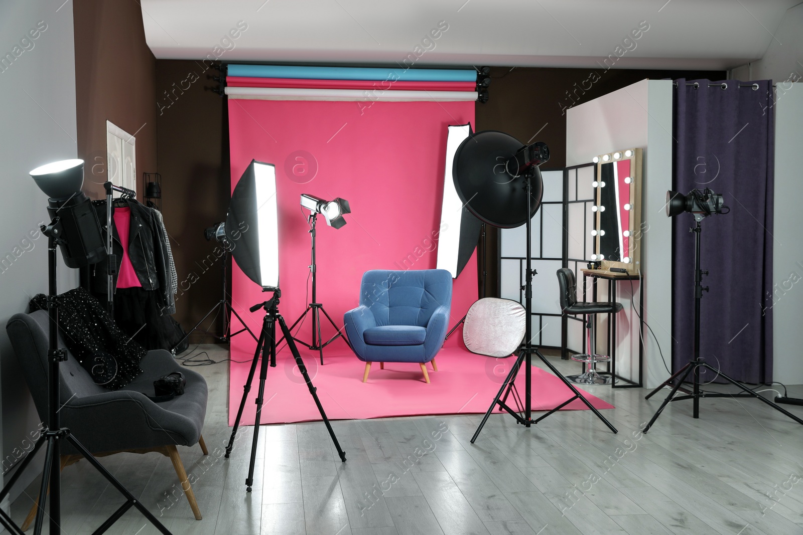 Photo of Stylish blue armchair in photo studio with professional equipment