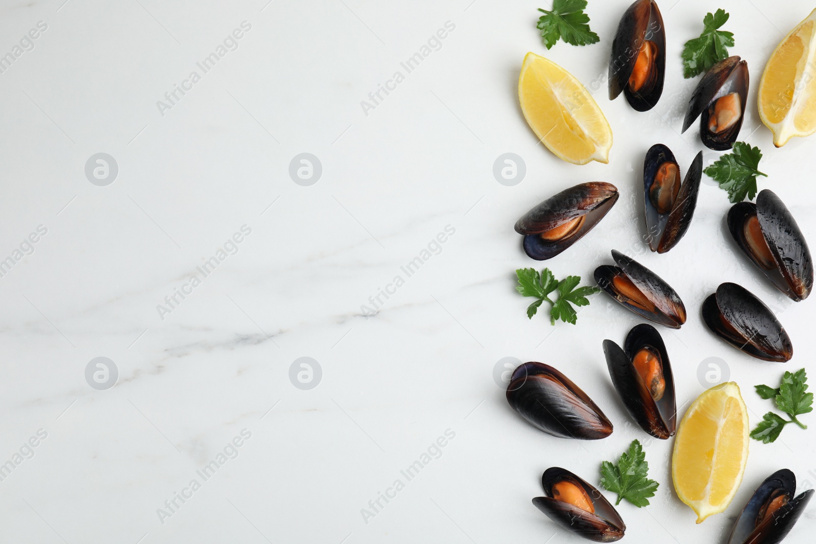 Photo of Cooked mussels with parsley and lemon on white marble table, flat lay. Space for text