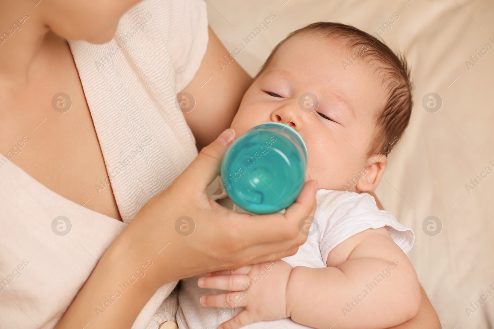 Photo of Mother feeding her cute child with infant formula indoors