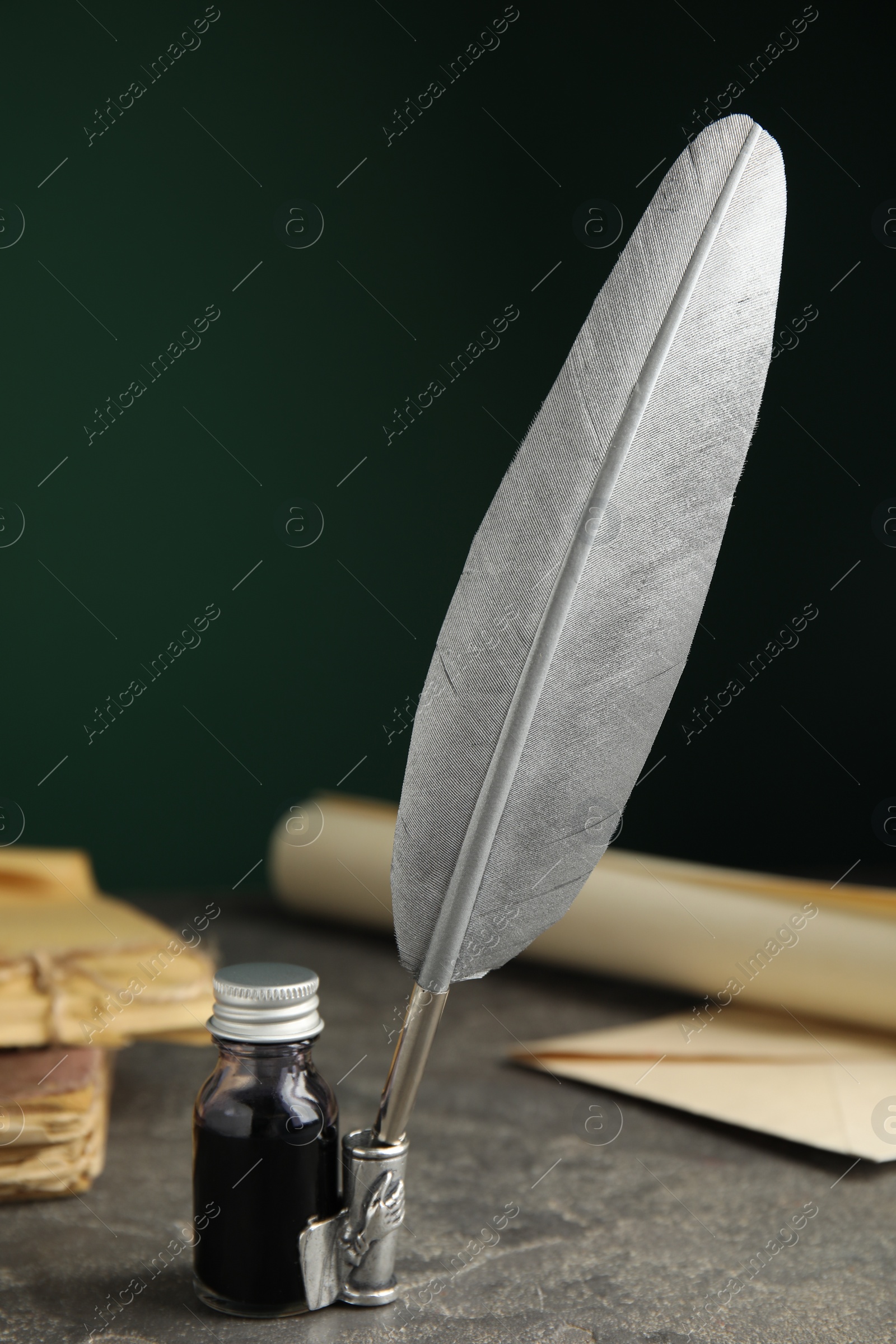 Photo of Composition with feather pen and bottle of ink on grey table