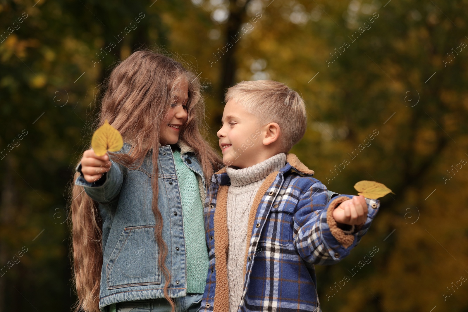 Photo of Portrait of happy children with autumn dry leaves in park