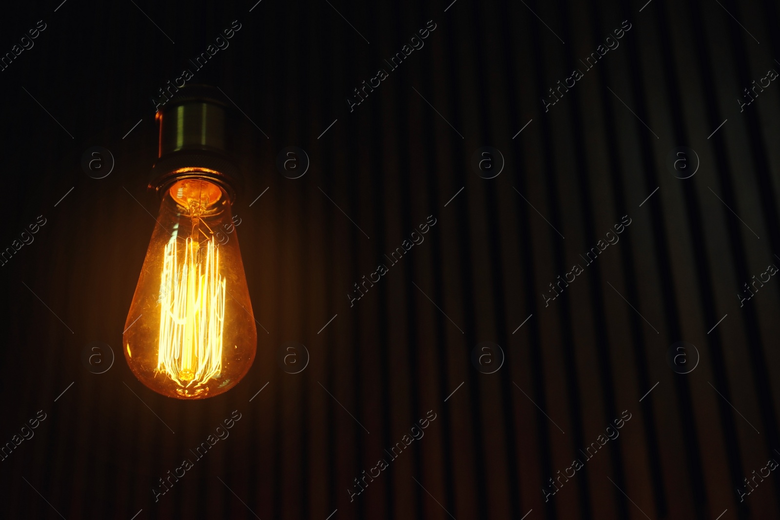 Photo of Pendant lamp with light bulb on wooden background. Space for text