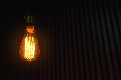 Photo of Pendant lamp with light bulb on wooden background. Space for text