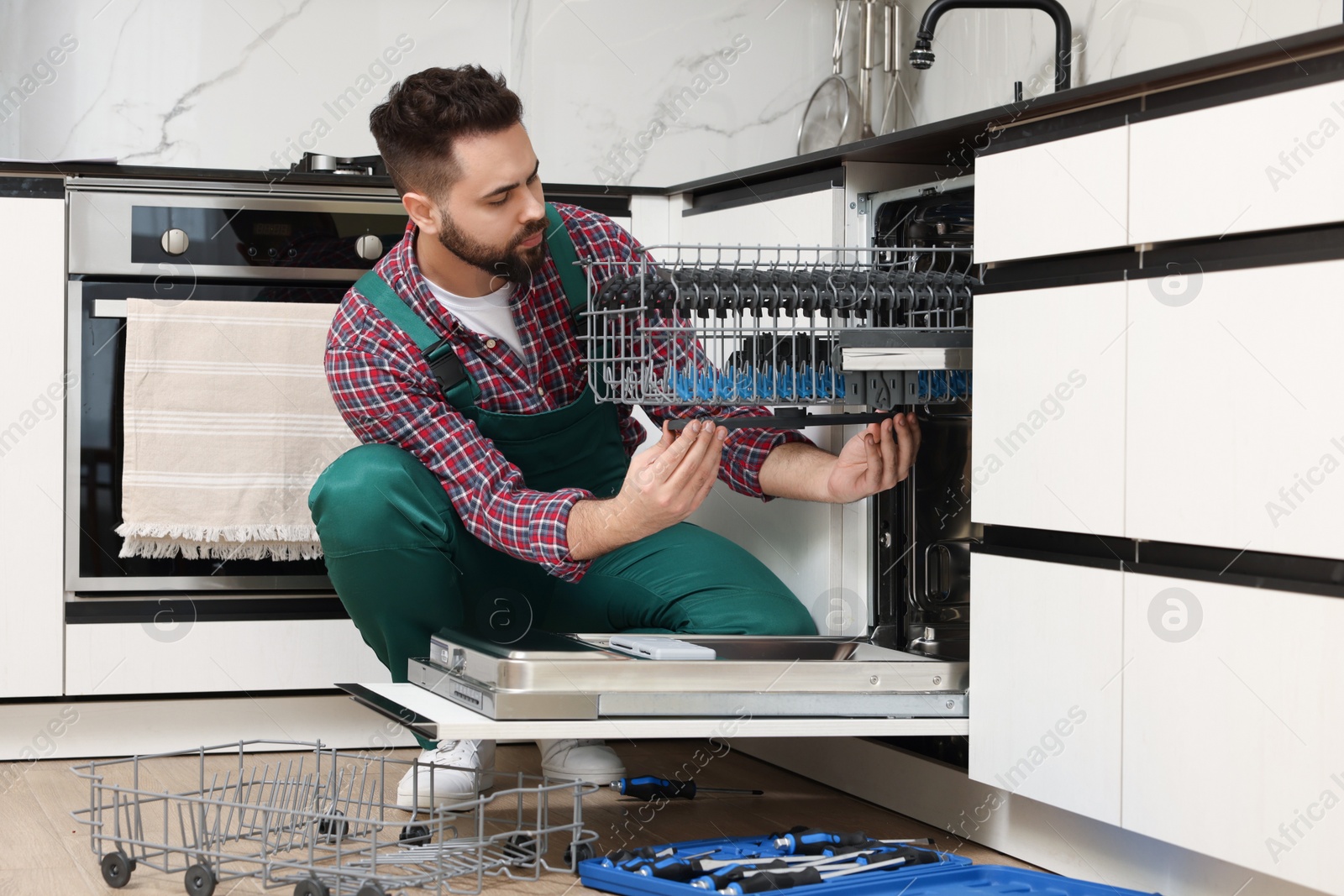 Photo of Serviceman repairing dishwasher cutlery rack in kitchen