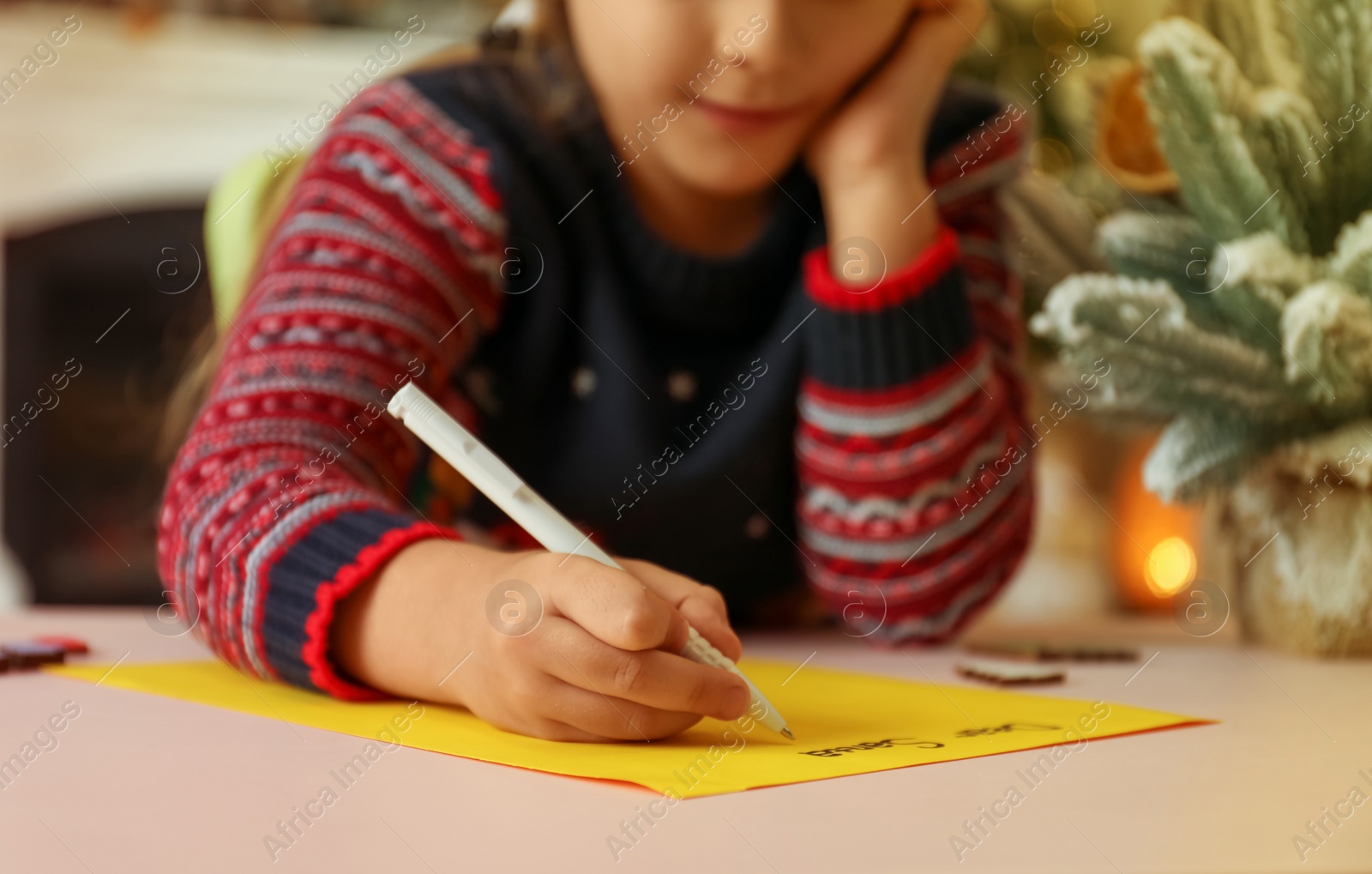 Photo of Cute child writing letter to Santa Claus at table, closeup. Christmas tradition