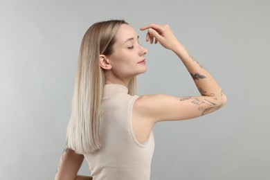 Portrait of beautiful tattooed woman on gray background